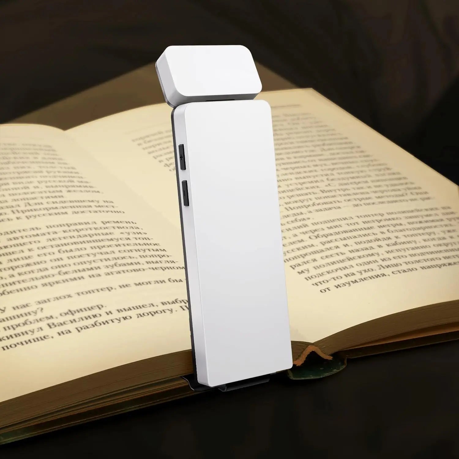 Detalhe da Luminária LED BookMark  branca iluminando apenas a página do livro, destacando a ausência de luz azul.