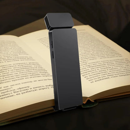 Detalhe da Luminária LED BookMark preta iluminando apenas a página do livro, destacando a ausência de luz azul.