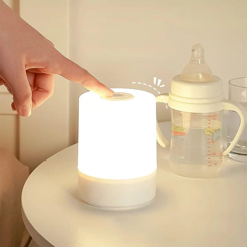 Mão tocando o topo da Luminária de Mesa para ajustar o brilho suave durante a noite.
