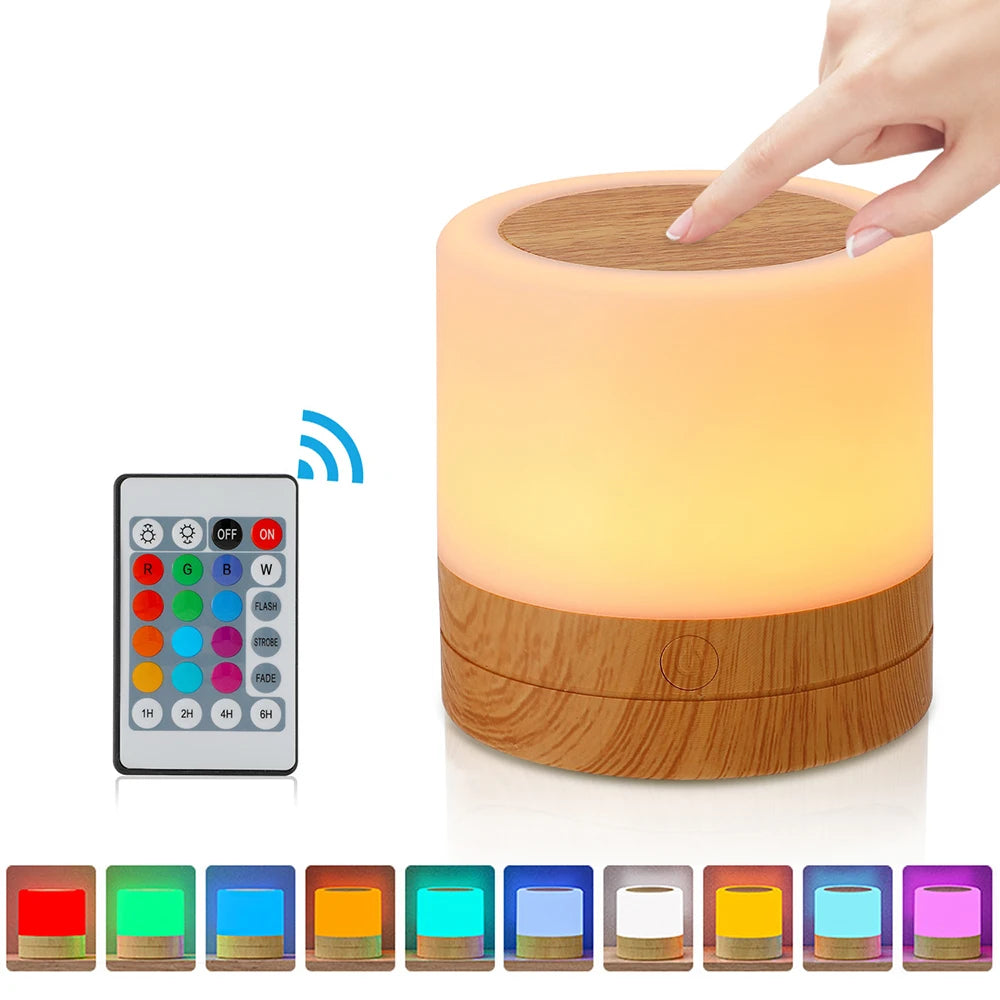 Luminária para quarto Aura 360 com base amadeirada emitindo luz quente suave em diversas cores e controle no fundo branco. 