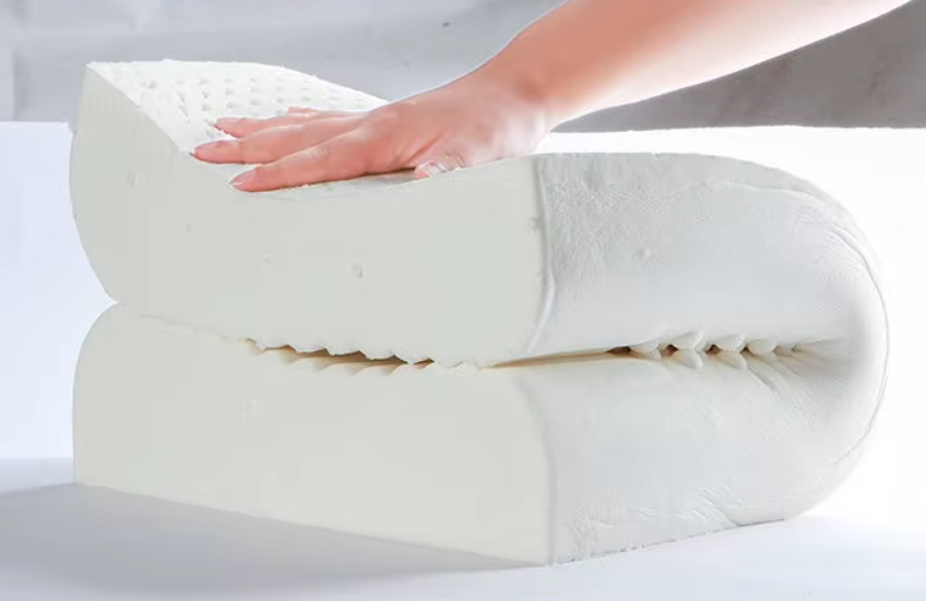 Mão dobrando o travesseiro ortopédico Sillencia LatexPro destacando a espuma de memória.