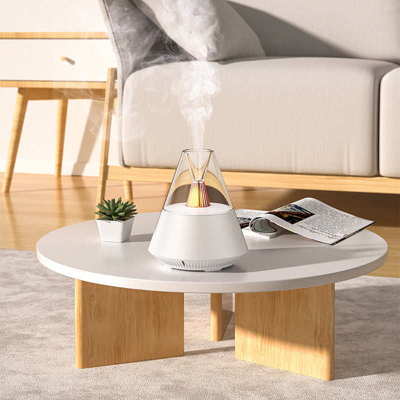 Umidificador de ar Sillencia VolcanoMist em branco liberando névoa com luz de chama interna em uma mesa de centro