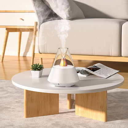 Umidificador de ar Sillencia VolcanoMist em branco liberando névoa com luz de chama interna em uma mesa de centro