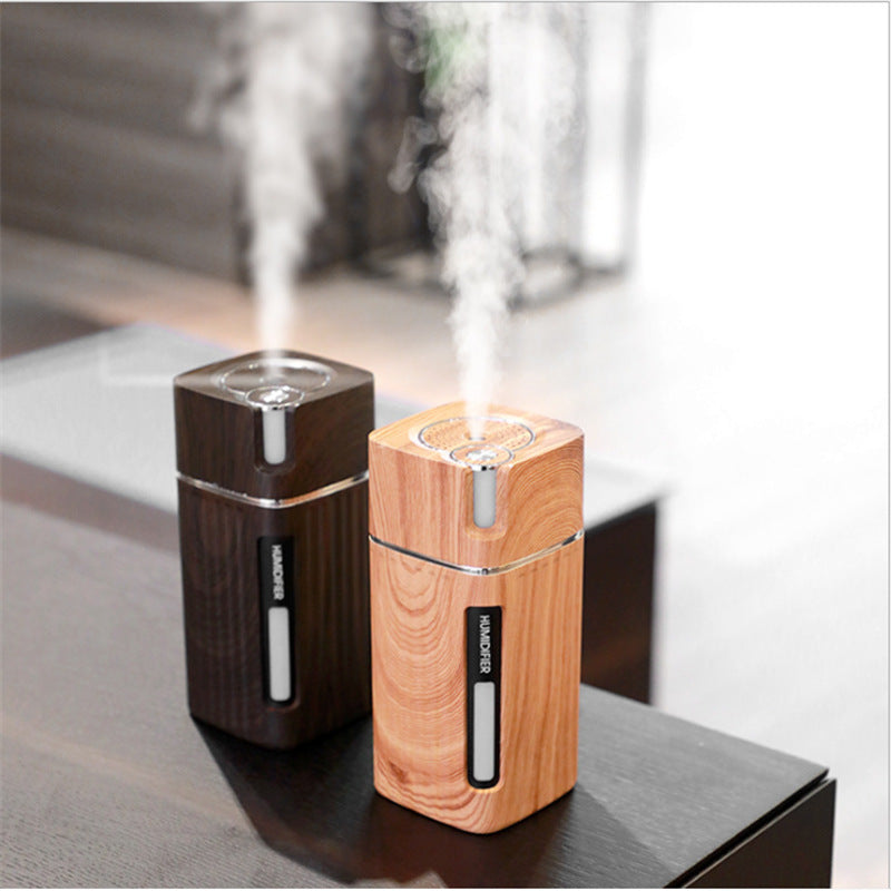 Umidificador de ar Sillencia WoodMist em textura amadeirada clara e escura liberando névoa fina em cima de uma mesa.