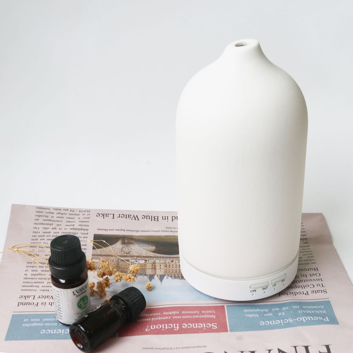 Umidificador de ar Sillencia ZenMist Ceramic em branco com óleos essenciais ao lado